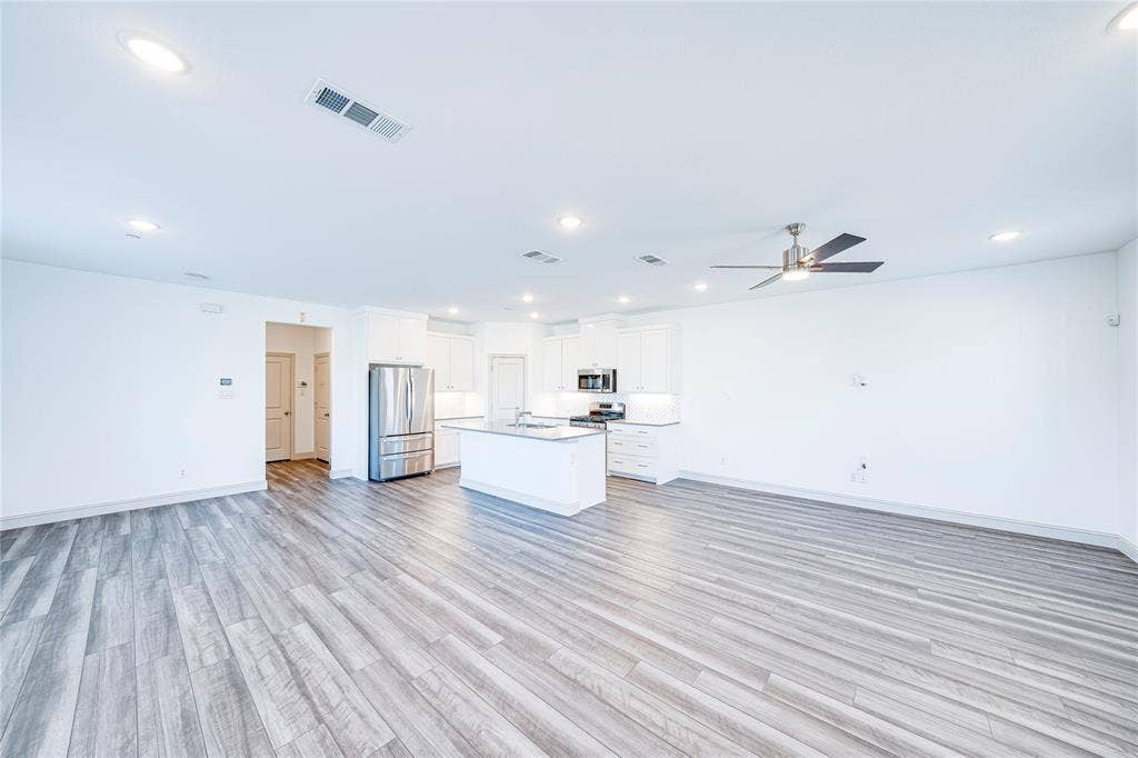 8888 Samara Street, Frisco, TX 75035 Open-concept living space featuring wood-finish flooring, recessed lighting, a modern ceiling fan, and a kitchen with an island and stainless steel appliances