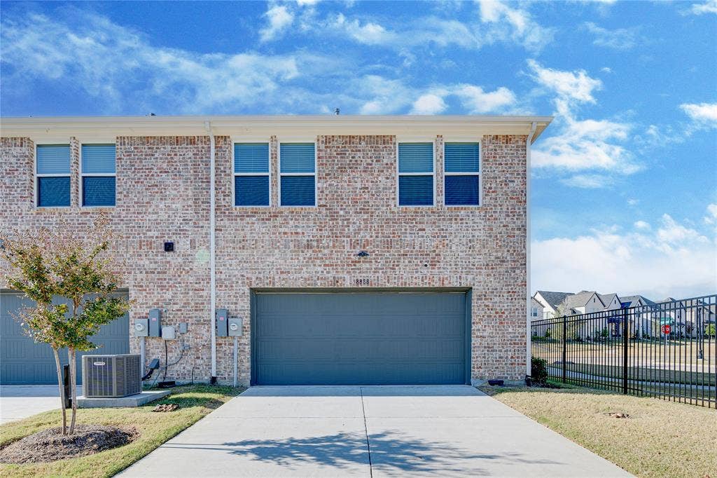 8888 Samara Street, Frisco, TX 75035 Brick exterior with white window frames, an attached garage, a concrete driveway, and a black metal fence