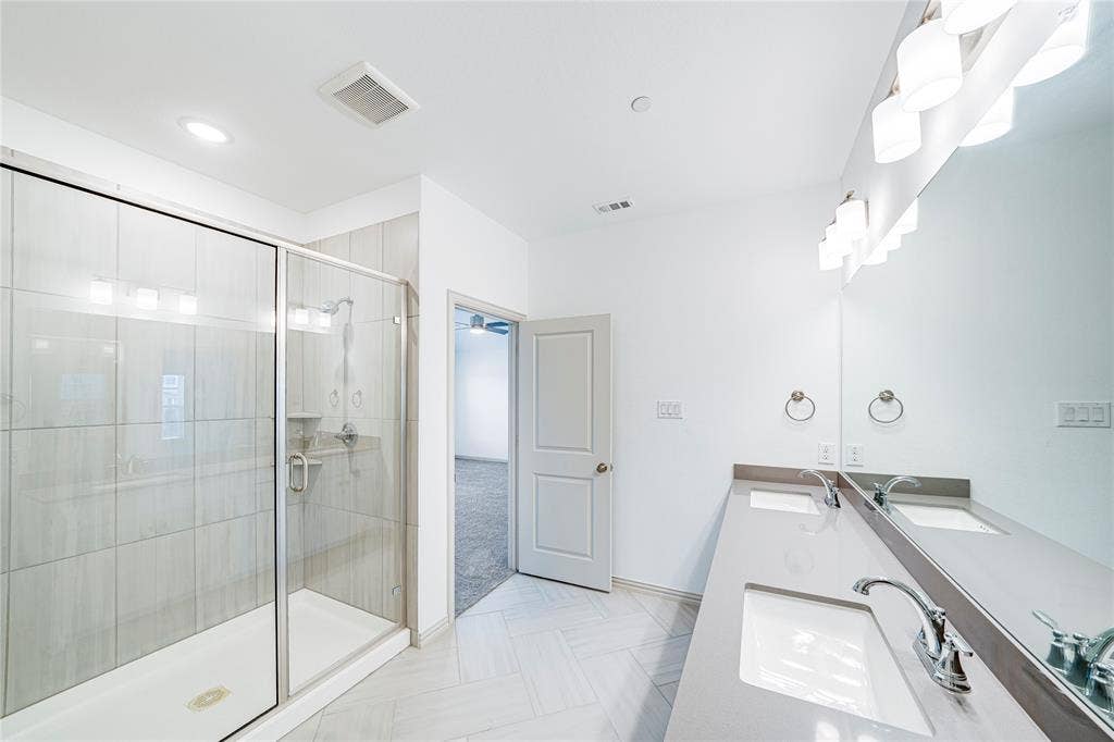 8888 Samara Street, Frisco, TX 75035 Glass-enclosed shower with subway tile surround, dual vanity with undermount sinks, and a full-width mirror