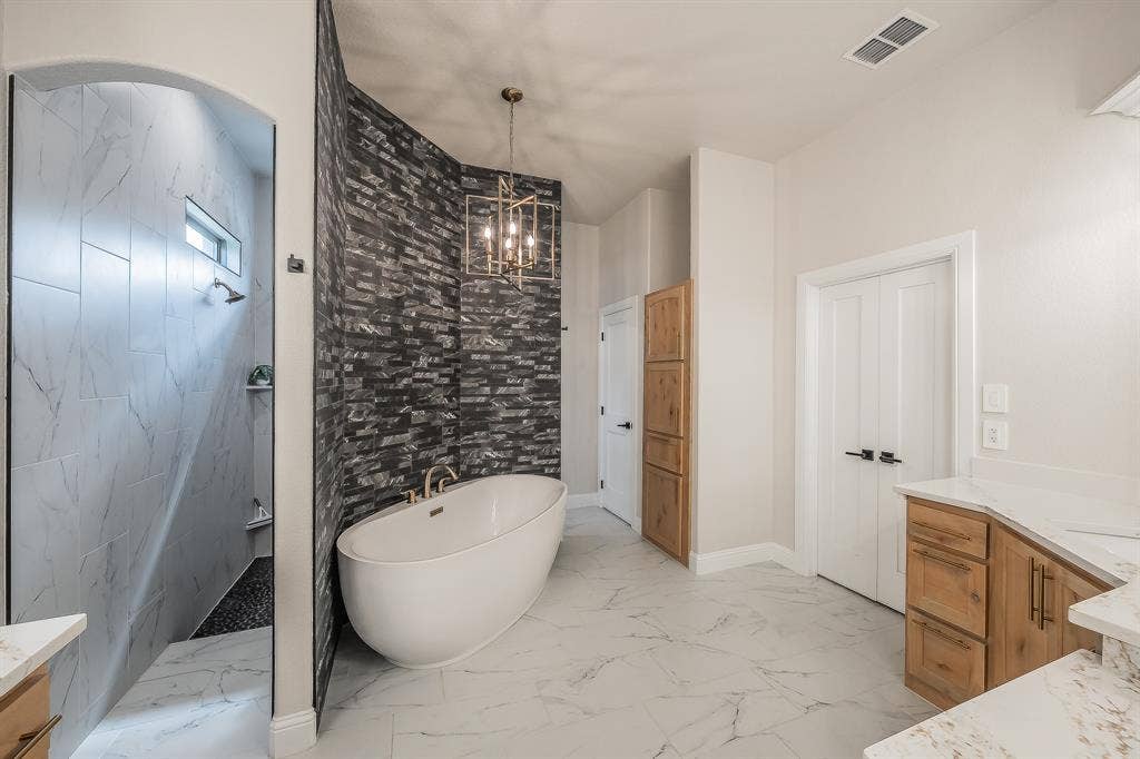 Private walk-through double shower, freestanding tub, and double doors to the closet.
