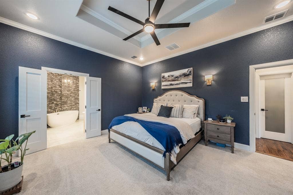 Trimmed tray ceiling, wall sconce lighting, & double doors to the Primary Bath.