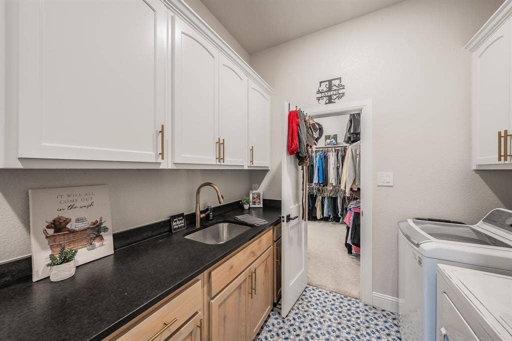 It's so convenient when the utility room opens to the primary closet. Lots of cabinets, undermount sink, and designer tile flooring.