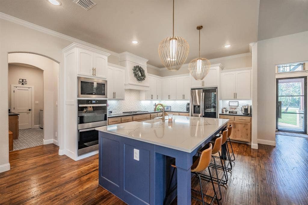 Double ovens, 5-burner gas cooktop, farm sink in the oversized island with storage galore! Pendant lights are perfect!