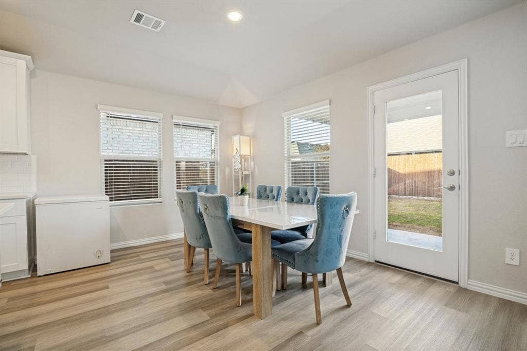 753 Poppy Lane, Lavon, TX 75166 Neutral-toned interior space featuring wood-finish flooring, three double-pane windows with horizontal blinds, and a full-glass panel door