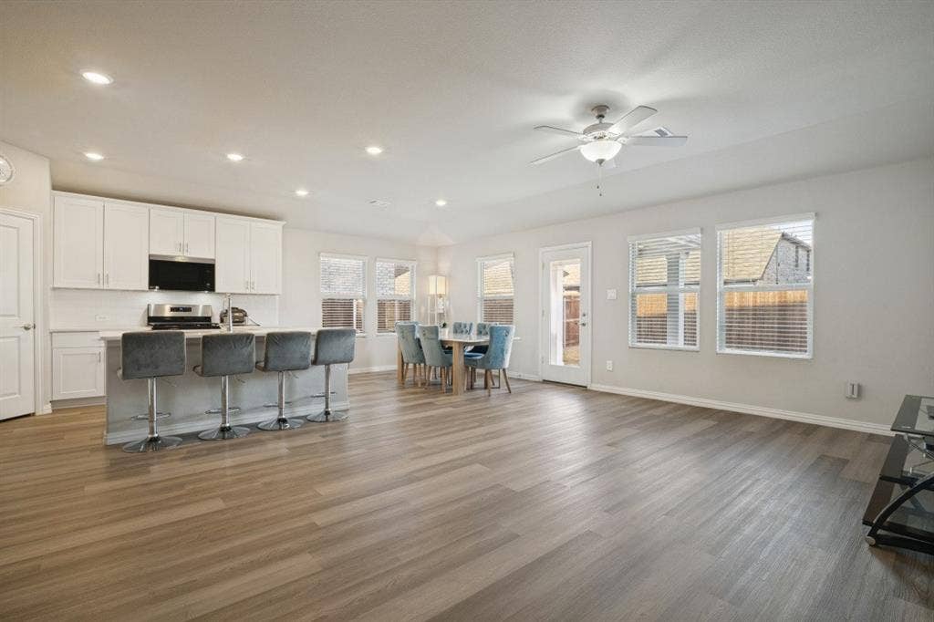 753 Poppy Lane, Lavon, TX 75166 Open-concept interior featuring wood-finish flooring, white shaker-style cabinetry, a central kitchen island, recessed lighting, and a ceiling fan