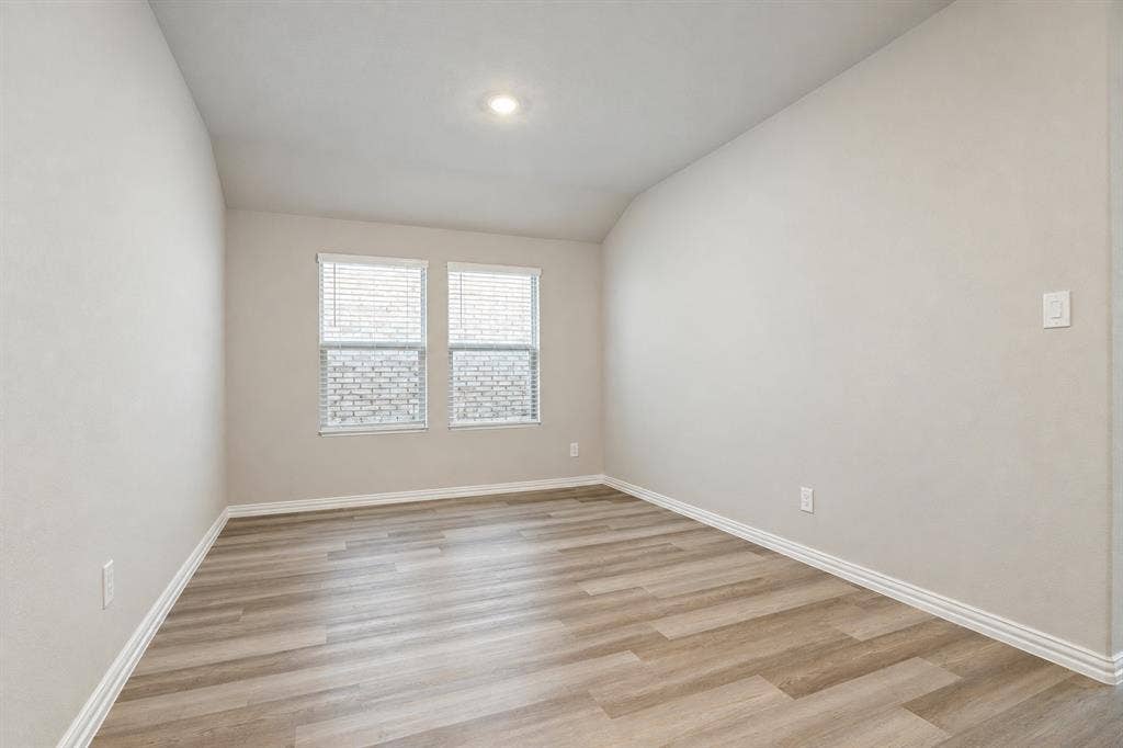 753 Poppy Lane, Lavon, TX 75166 Neutral-toned interior space featuring wood-finish flooring, vaulted ceiling, and dual double-pane windows