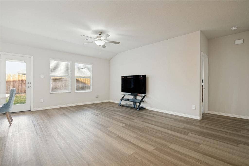 753 Poppy Lane, Lavon, TX 75166 Neutral-toned interior featuring wood-finish flooring, a ceiling fan with integrated lighting, dual windows with blinds, and a glass-paneled exterior door