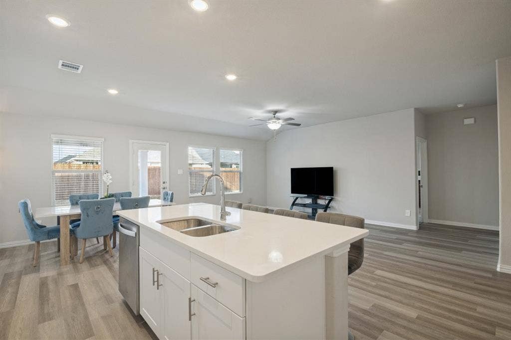 753 Poppy Lane, Lavon, TX 75166 Kitchen island with stone countertop, stainless steel dual-basin undermount sink, white shaker-style cabinetry, recessed lighting, and wood-finish flooring