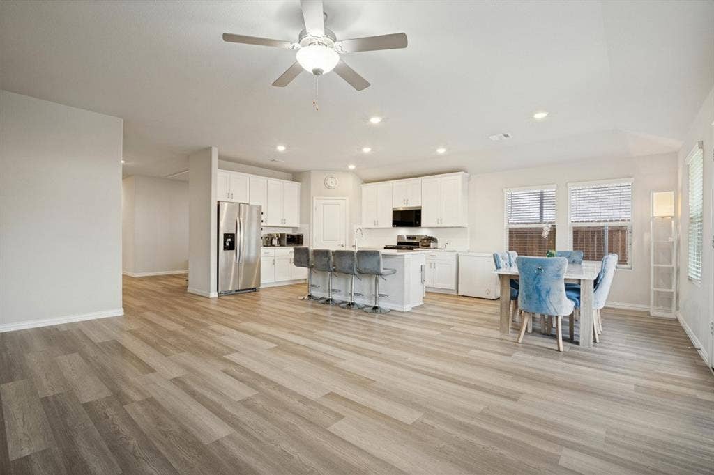 753 Poppy Lane, Lavon, TX 75166 Open-concept kitchen featuring white cabinetry, a center island, stainless steel appliances, wood-finish flooring, and recessed ceiling lighting