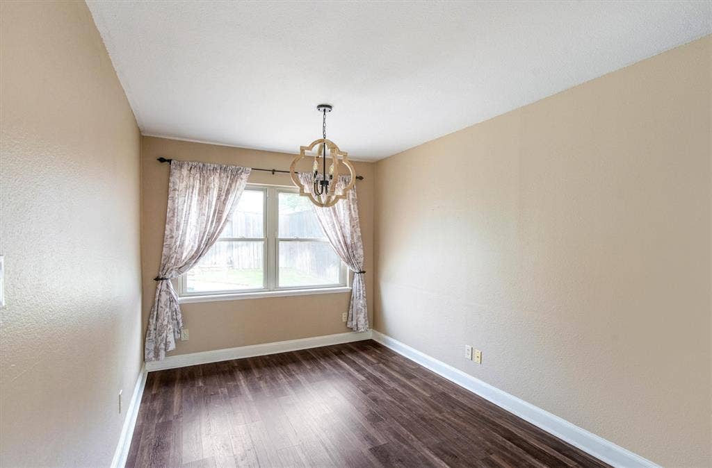 Room featuring luxury vinyl plank flooring, a multi-pane window, and a decorative chandelier light fixture