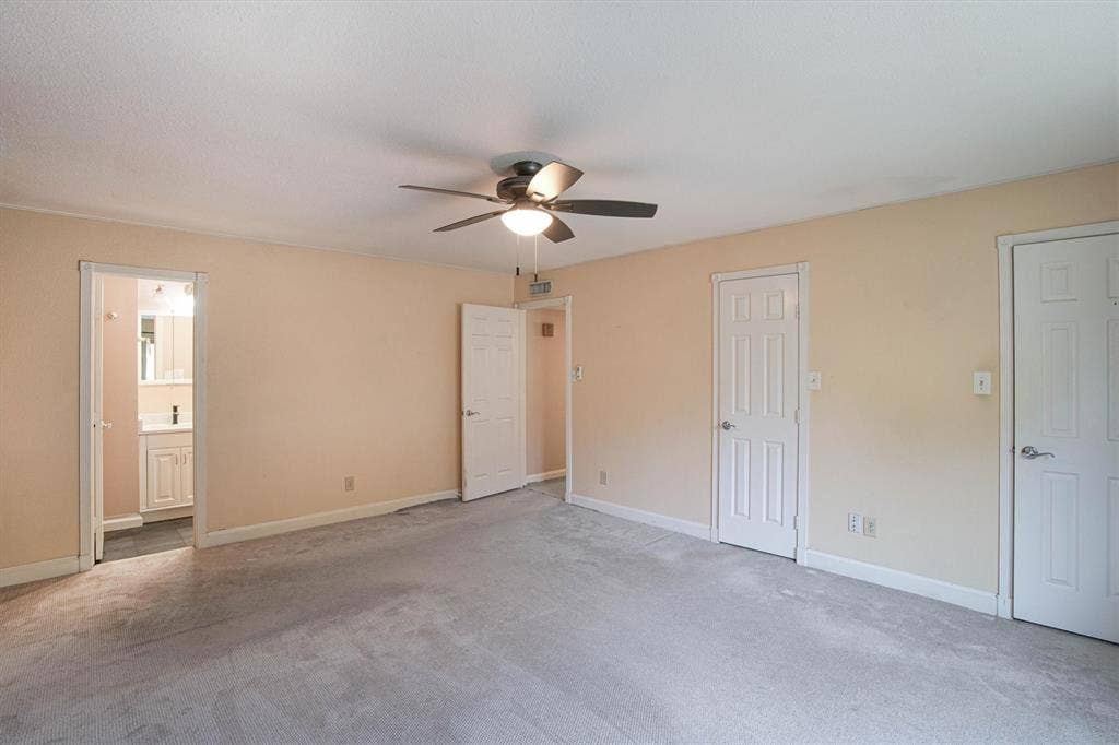 Neutral-toned interior featuring wall-to-wall carpeting, a ceiling fan with integrated lighting, and multiple six-panel interior doors