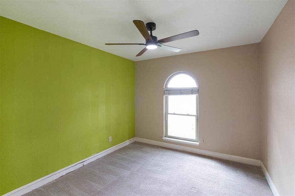 Interior room featuring wall-to-wall carpeting, an arched window, and a ceiling fan with integrated lighting