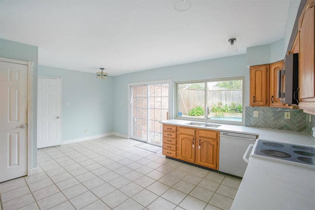 Eat-in kitchen featuring wood cabinetry, herringbone pattern backsplash, quartz countertops, ceramic tile flooring, and double paned sliding glass doors