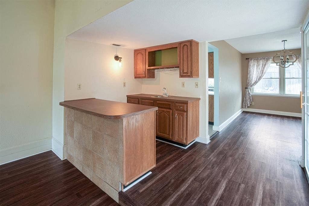 Wet bar featuring wood cabinetry, a sink, and a tiled bar-front  complemented by luxury vinyl flooring