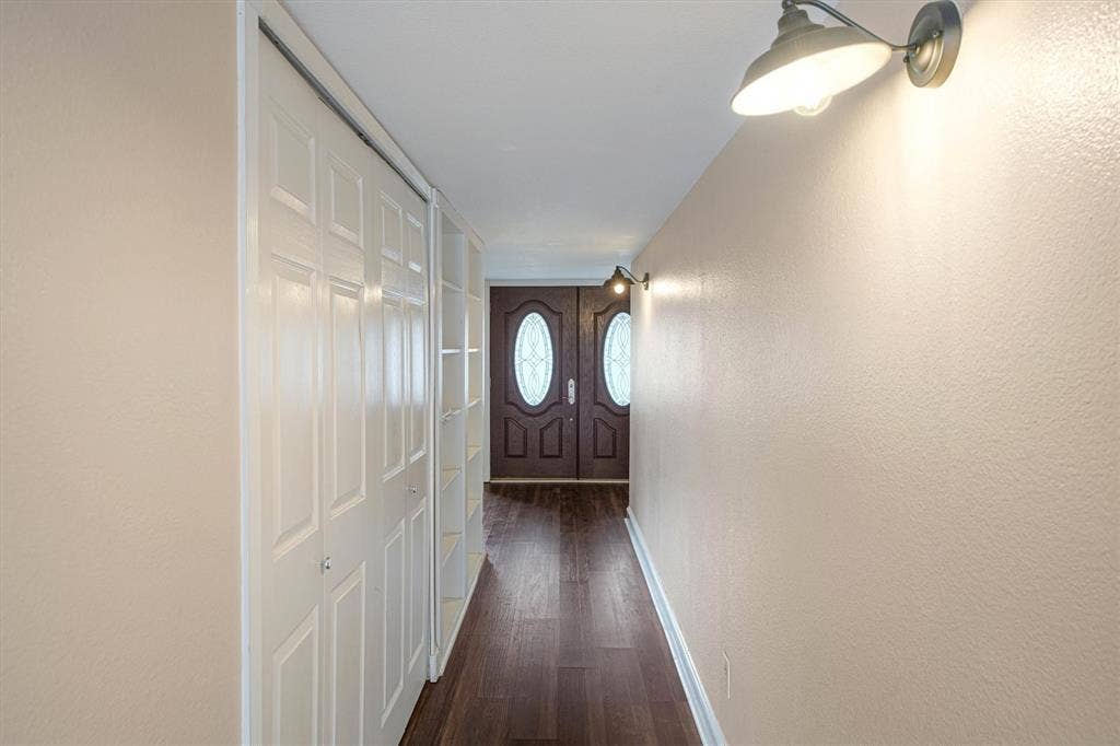 Entryway featuring double doors with oval glass inserts, luxury vinyl plank flooring, built-in shelving, utility closet, and industrial-style wall-mounted lighting fixtures