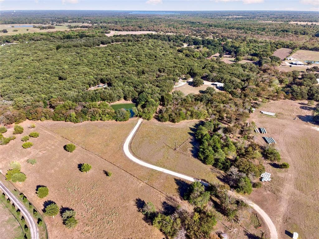 Expansive parcel featuring a private pond, mature trees, and a winding gravel driveway