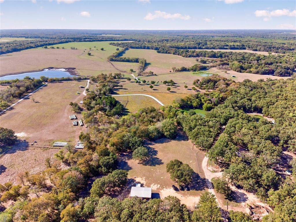 Expansive rural property featuring an abundance of mature trees, open pastures, and a private pond