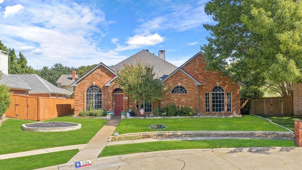 5104 Teddington Park Drive, Plano, TX 75023 Brick exterior with an arched entry, prominent arched windows, and a manicured lawn