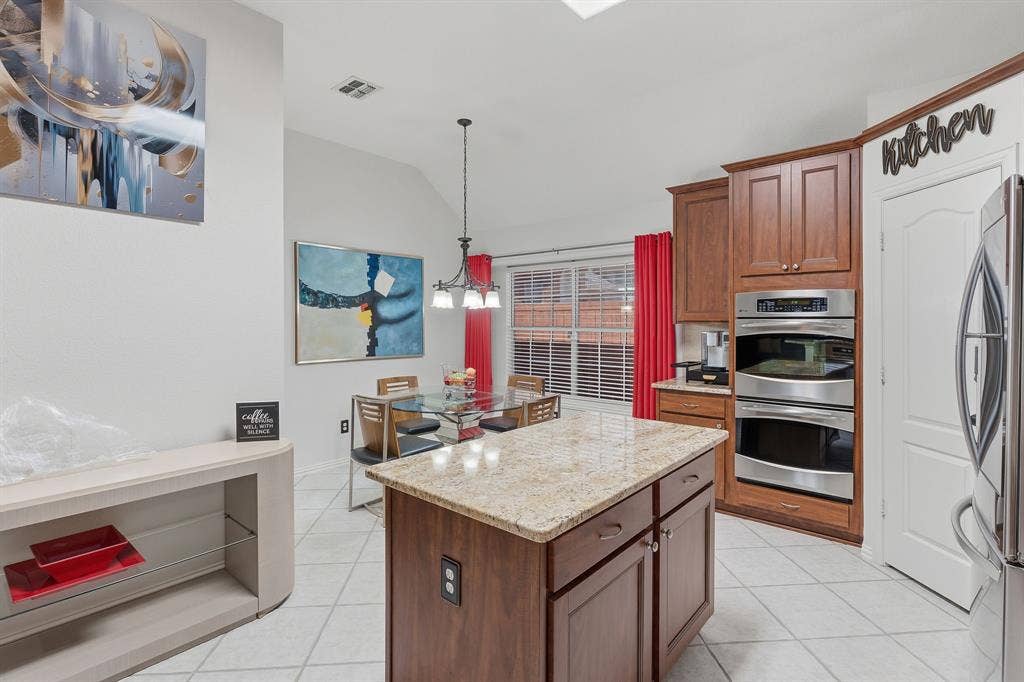 5104 Teddington Park Drive, Plano, TX 75023 Kitchen island with granite countertop, wood cabinetry, stainless steel double oven, and tiled flooring