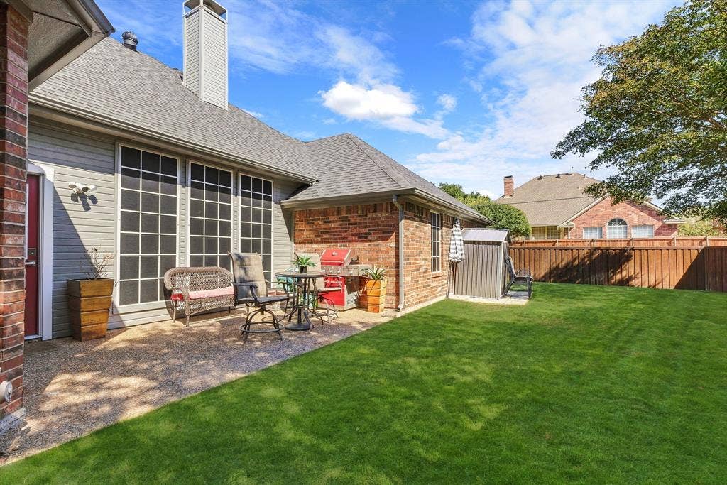 5104 Teddington Park Drive, Plano, TX 75023 Expansive backyard with a manicured lawn, full privacy fencing, and a stone-finish patio area
