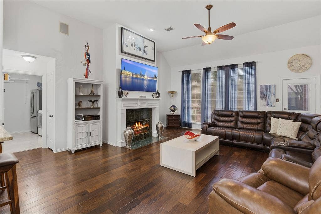 5104 Teddington Park Drive, Plano, TX 75023 Hardwood-style flooring throughout, vaulted ceiling, and a fireplace with a white mantel and tile surround