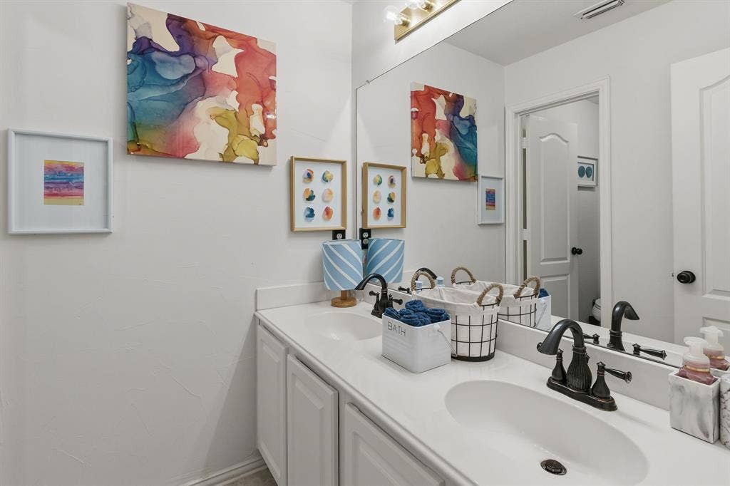 5104 Teddington Park Drive, Plano, TX 75023 Double vanity with white cabinetry, solid surface countertop, dual undermount sinks, and oil-rubbed bronze fixtures