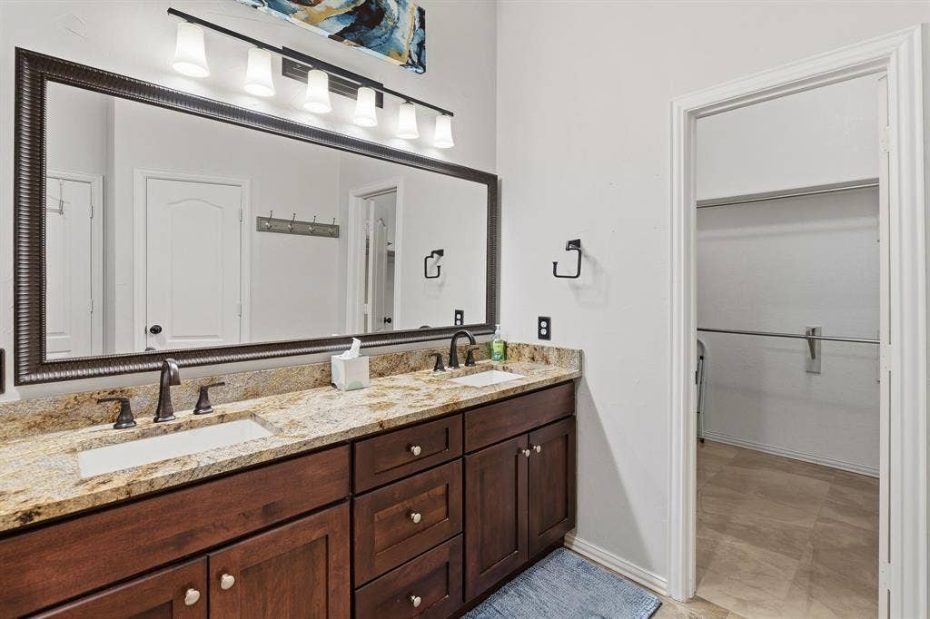 5104 Teddington Park Drive, Plano, TX 75023 Dual vanity with undermount sinks, granite countertop, dark wood-finish cabinetry, and oil-rubbed bronze fixtures