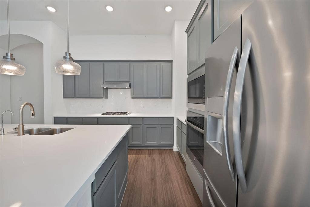 1553 Wyler Drive, Forney, TX 75126 Kitchen featuring gray shaker cabinetry, stainless steel appliances, white countertops, a gas range with a range hood, and wood-finish flooring