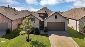 1553 Wyler Drive, Forney, TX 75126 Stone and brick facade home featuring an attached garage, a concrete driveway, and a front yard with mature landscaping