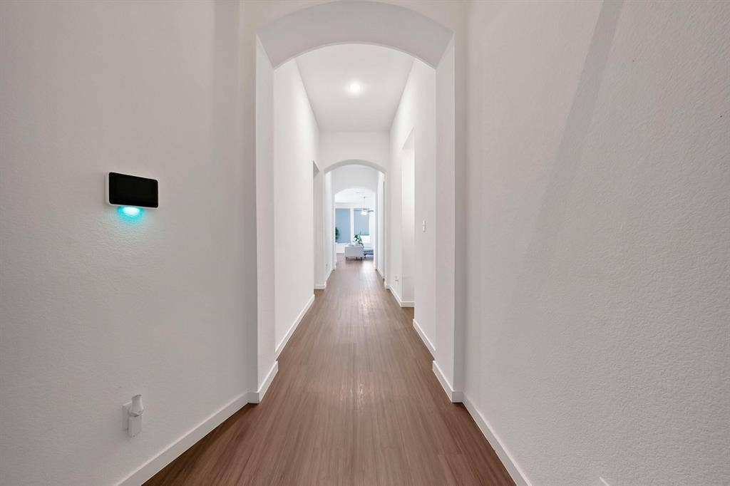 1553 Wyler Drive, Forney, TX 75126 Arched doorways define the hallway, featuring wood-finish flooring and recessed lighting