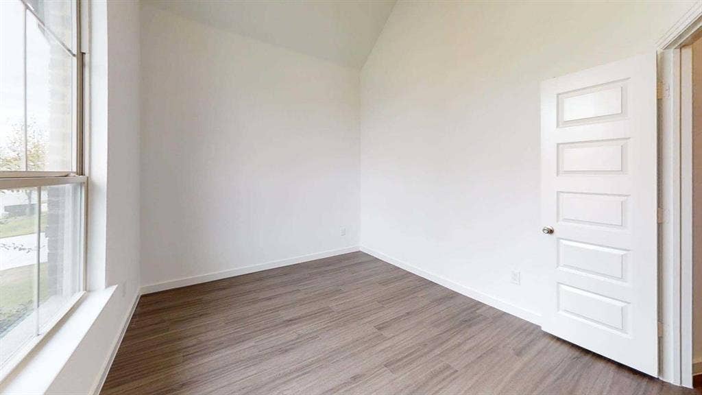 1553 Wyler Drive, Forney, TX 75126 Vaulted ceiling, large window, wood-finish flooring, white paneled door, and neutral wall tones
