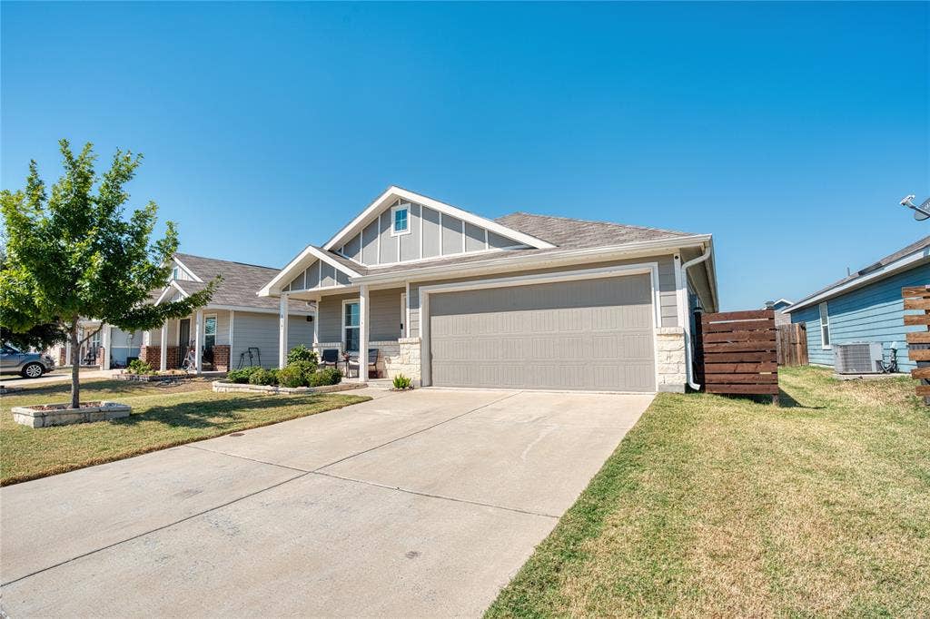 554 Deerfern Drive, Princeton, TX 75407 Attached two-car garage with a concrete driveway, a covered front porch, and a stone accent facade