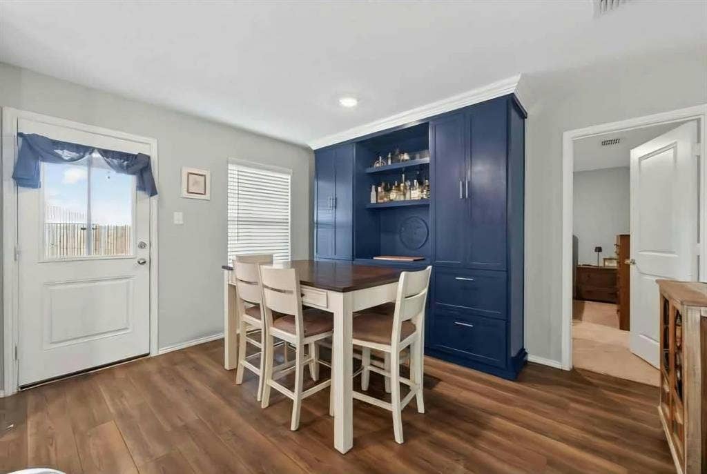554 Deerfern Drive, Princeton, TX 75407 Wood-finish flooring throughout, built-in blue cabinetry with open shelving, recessed lighting, and a window with blinds
