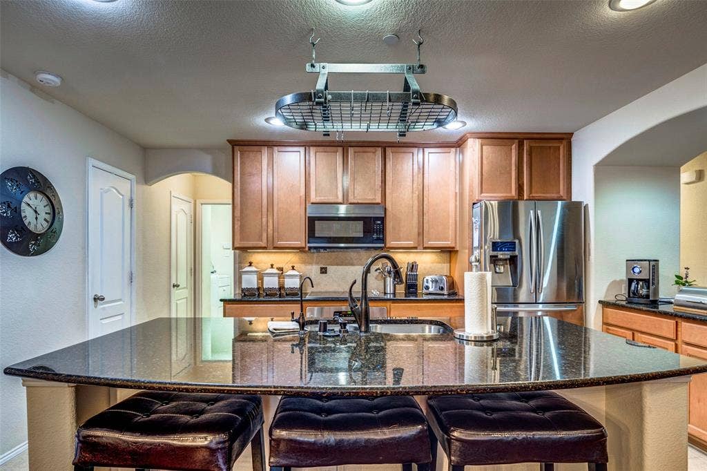 1040 Lucy Lane, Allen, TX 75013 Kitchen featuring a large island with an undermount sink, granite countertops, wood cabinetry, and stainless steel appliances