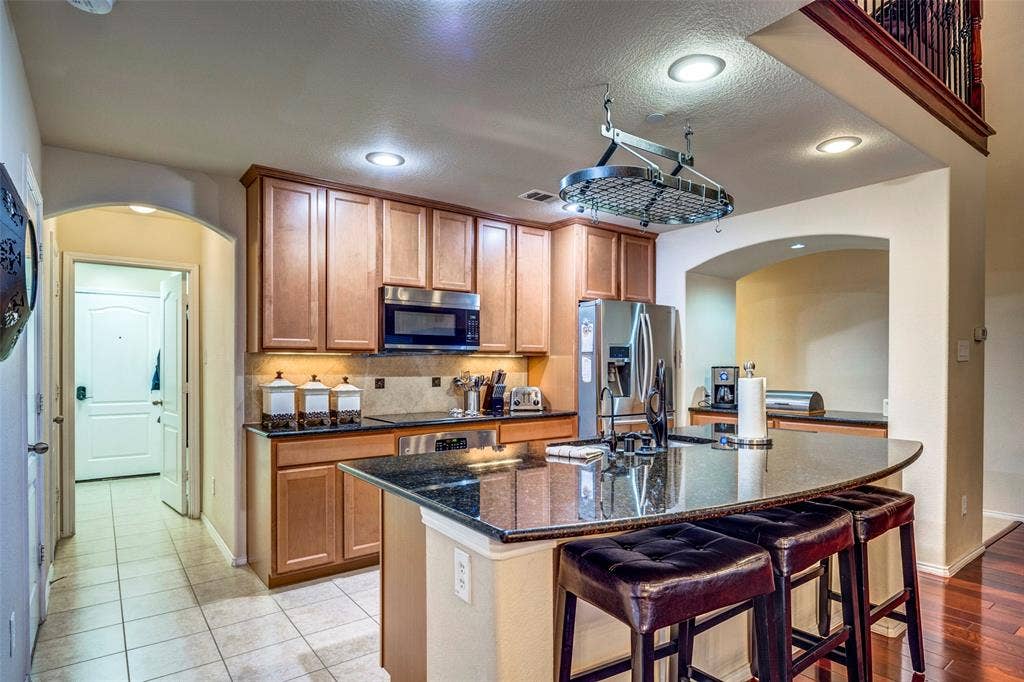 1040 Lucy Lane, Allen, TX 75013 Kitchen featuring wood cabinetry, stainless steel appliances, recessed lighting, and an expansive island with a dark countertop