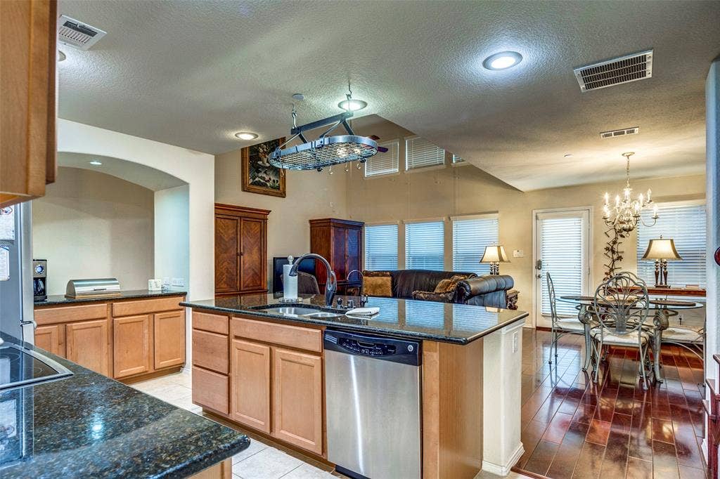 1040 Lucy Lane, Allen, TX 75013 Kitchen featuring granite countertops, wood cabinetry, stainless steel dishwasher, and a center island with sink
