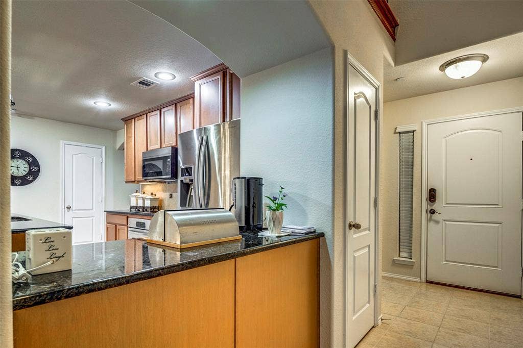 1040 Lucy Lane, Allen, TX 75013 Kitchen featuring wood cabinetry, stainless steel appliances, and dark granite countertops