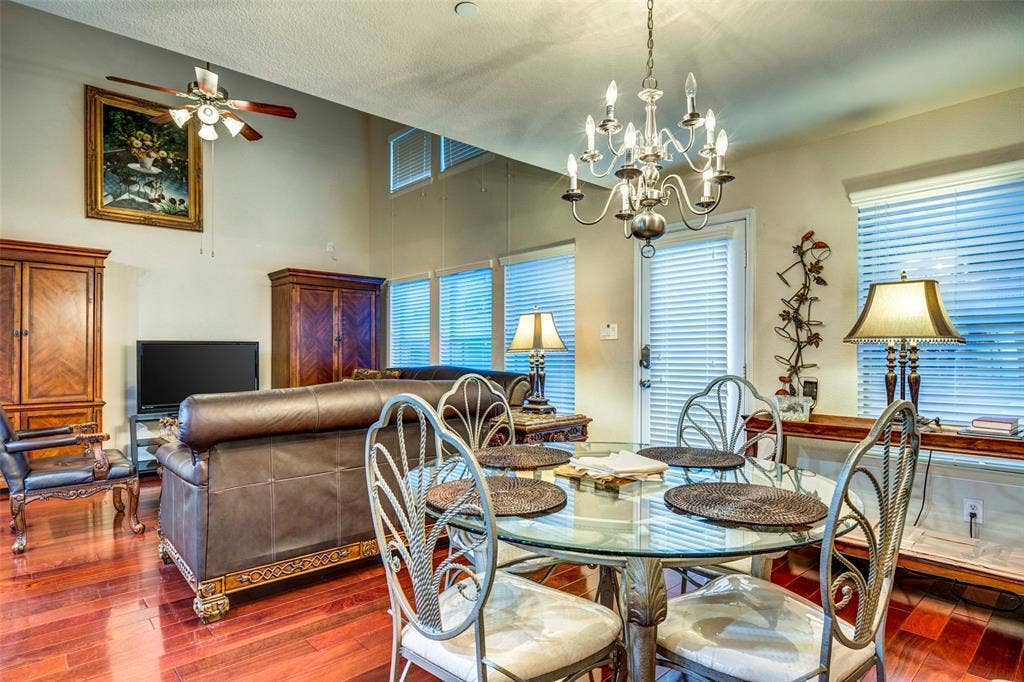 1040 Lucy Lane, Allen, TX 75013 Open-concept living area with high ceilings, wood-finish flooring, a contemporary chandelier, and multiple windows with horizontal blinds