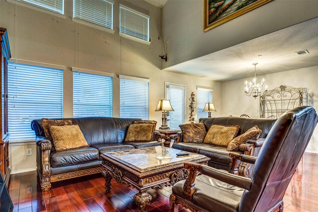 1040 Lucy Lane, Allen, TX 75013 High vaulted ceiling, multiple windows with blinds, wood-finish flooring, and a chandelier lighting fixture