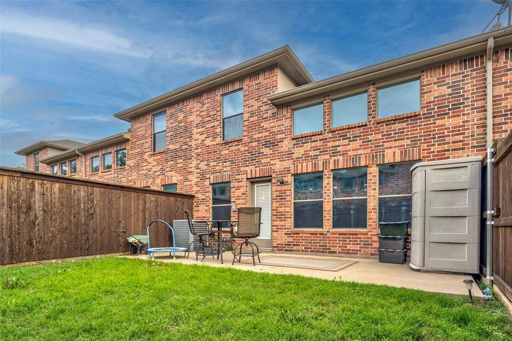 1040 Lucy Lane, Allen, TX 75013 Brick exterior with expansive rear patio featuring a concrete surface and manicured lawn