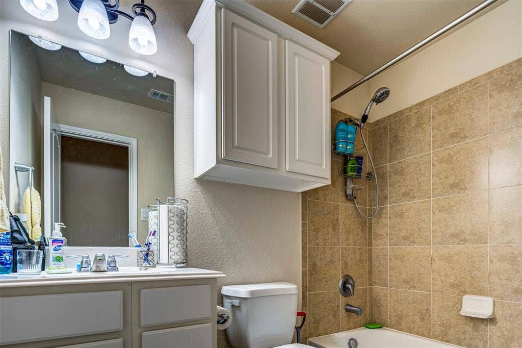 1040 Lucy Lane, Allen, TX 75013 Bathroom featuring a vanity with white cabinetry, a rectangular mirror, and a three-light fixture