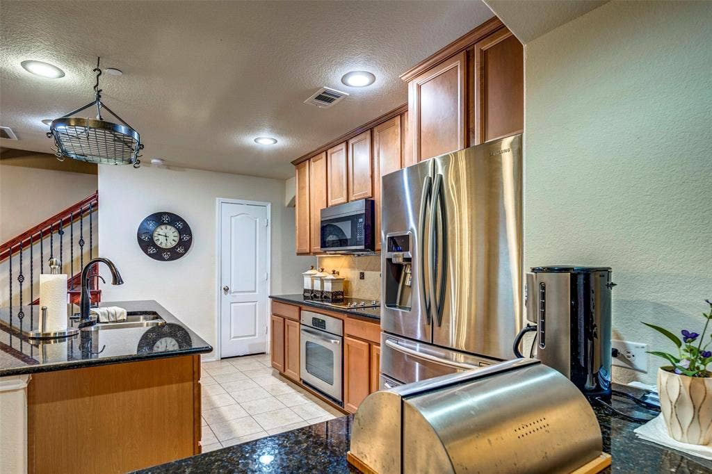 1040 Lucy Lane, Allen, TX 75013 Kitchen featuring black granite countertops, stainless steel appliances, wood cabinetry, recessed lighting, and tile flooring