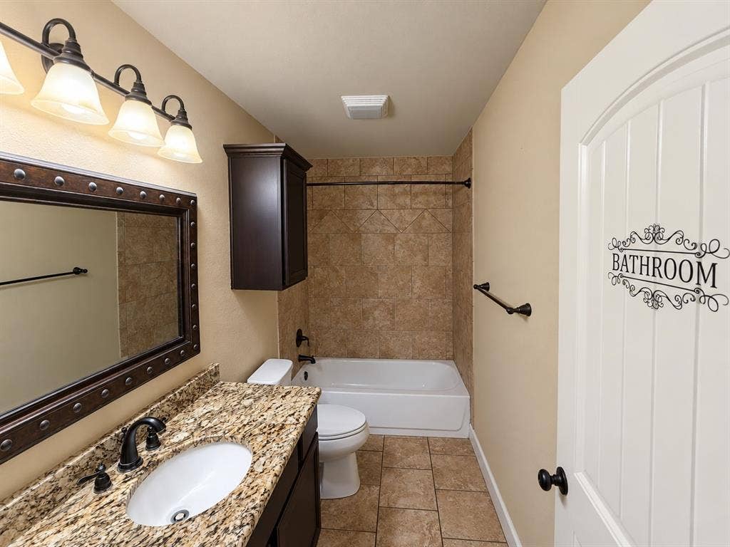 Vanity with a light-toned stone countertop, integrated oval sink, and dark bronze-finish faucet