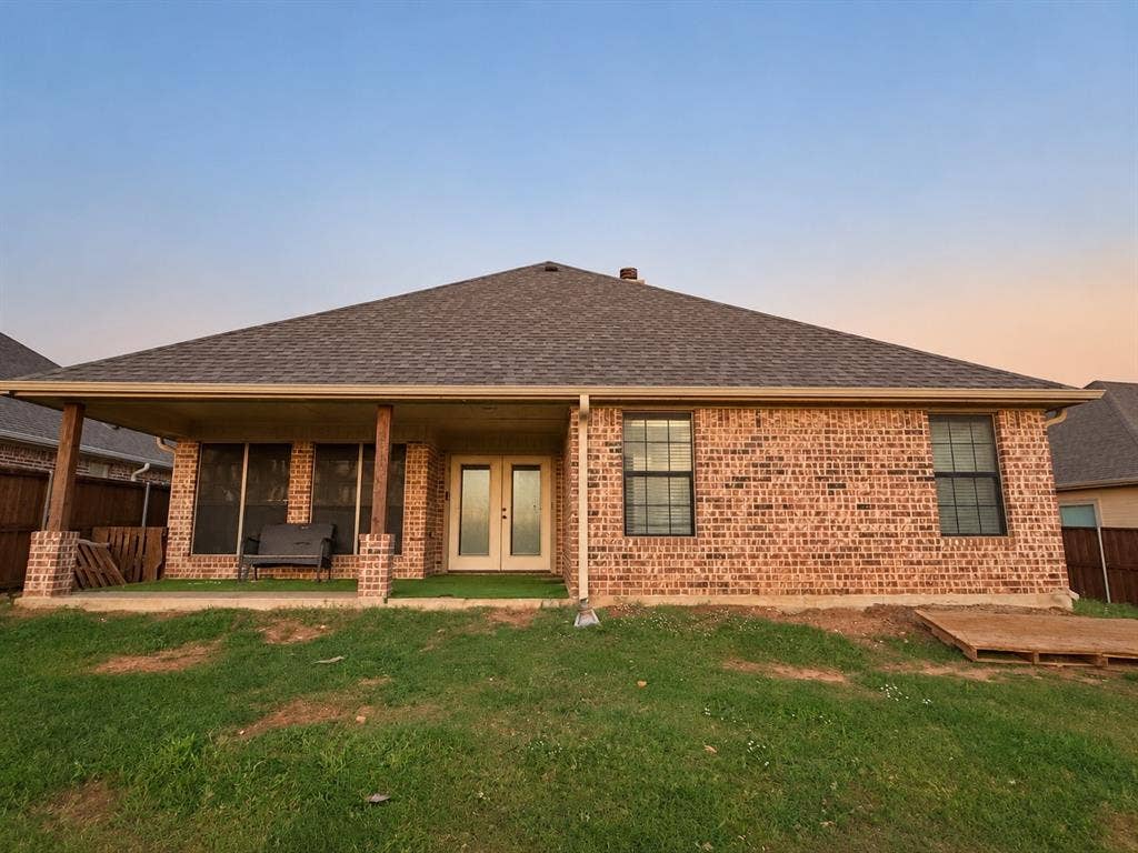 Brick exterior featuring a covered patio with columns, a shingle roof, and double-pane windows