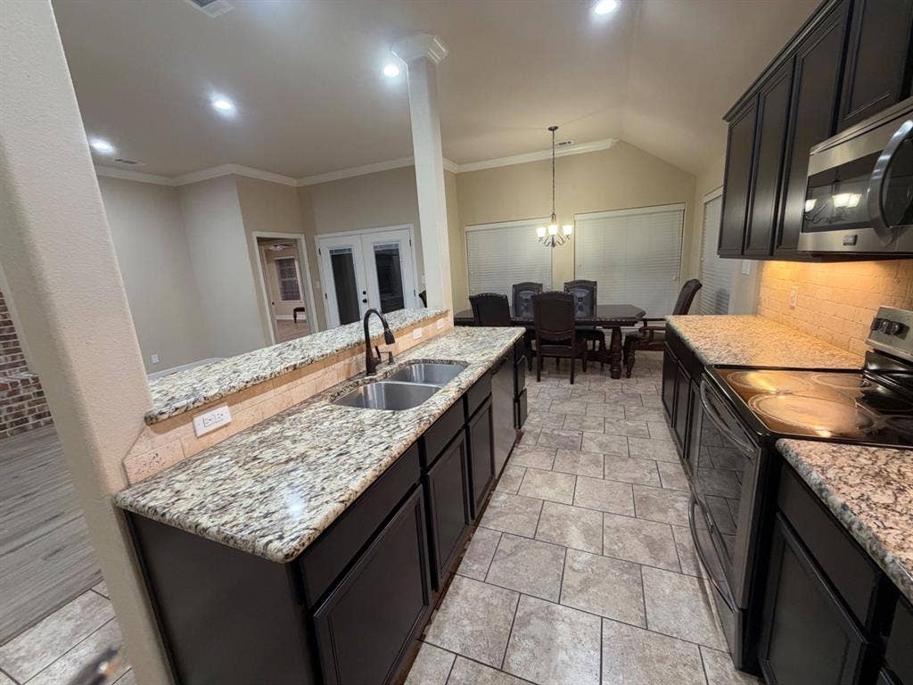 Kitchen with dark cabinetry, speckled countertops, stainless steel appliances, and a tile backsplash