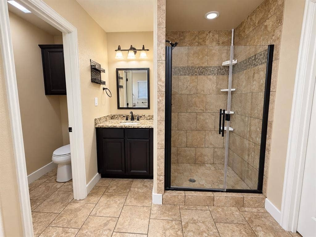 Tiled flooring complemented by a walk-in shower with glass enclosure and tiled surround