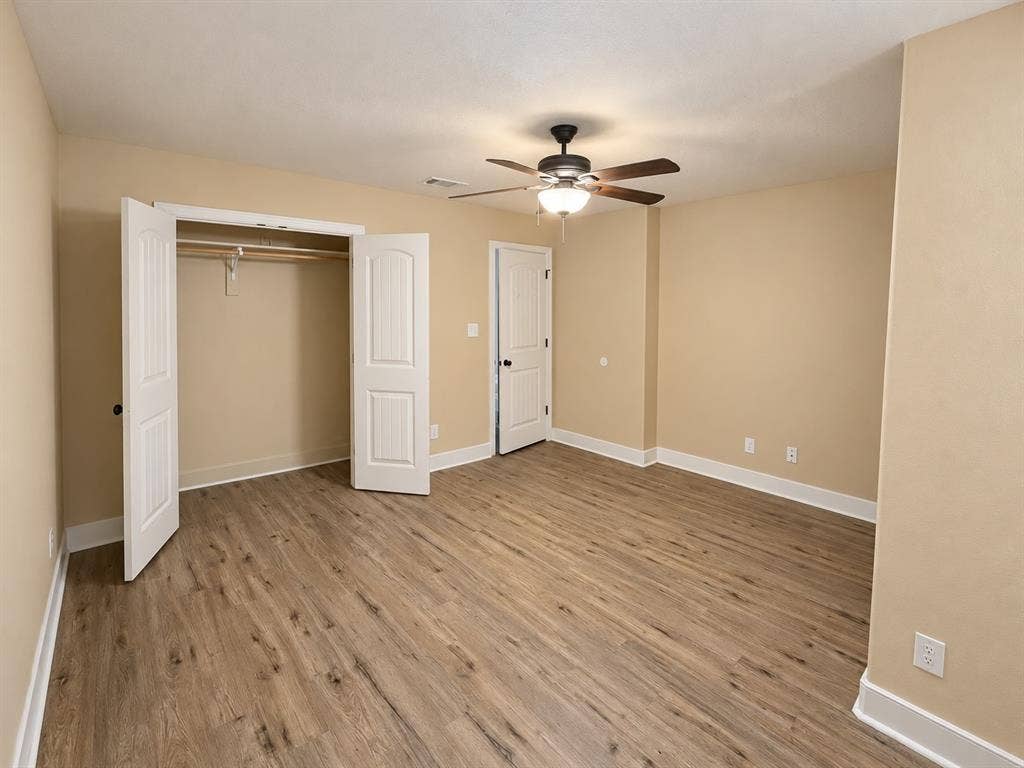Wood-finish flooring, ceiling fan with integrated lighting, and a built-in closet with double bifold doors