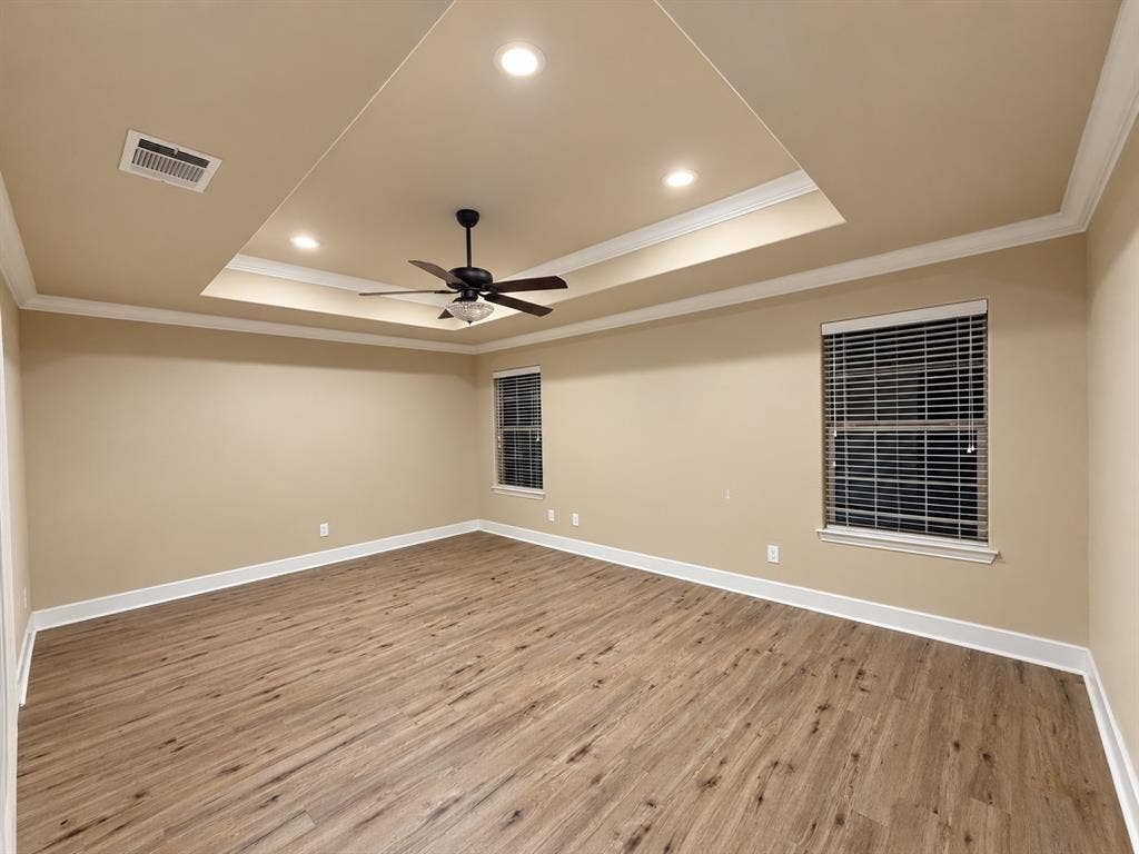 Tray ceiling with recessed lighting and a ceiling fan, wood-finish flooring, and two windows with blinds