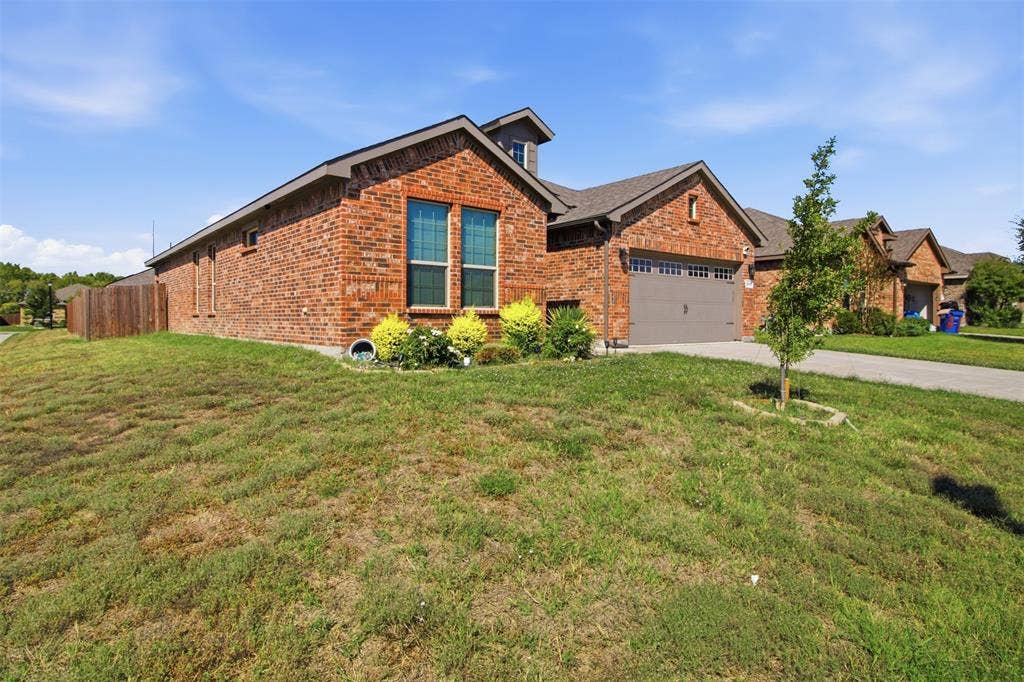 2513 Foules Drive, Glenn Heights, TX 75154 Red brick exterior, attached garage, gabled roofline, front landscaping, wood fence