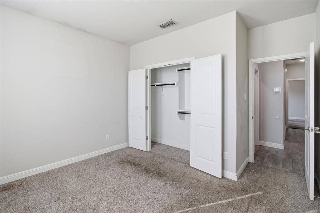 2513 Foules Drive, Glenn Heights, TX 75154 Spacious primary bedroom featuring neutral wall finishes, carpeted flooring, and dual closets with white frame doors and interior shelving